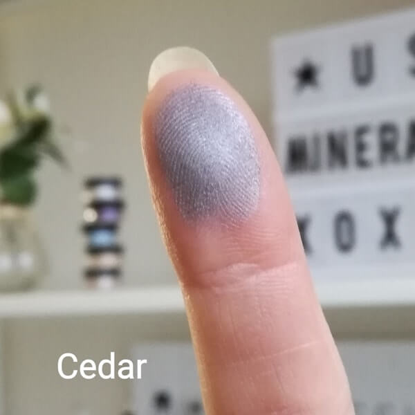 Swatch of Cedar mit grauem Schimmer on a fingertip