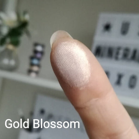 Schimmernder Swatch of Gold Blossom on a fingertip